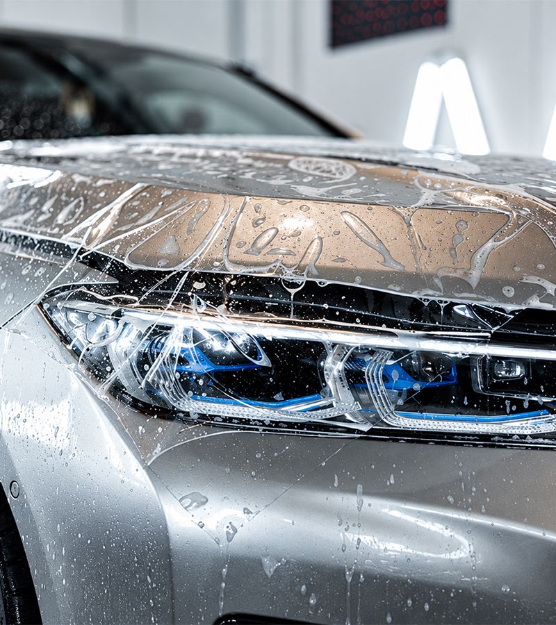 Clear paint protection film on a car headlight and bonnet